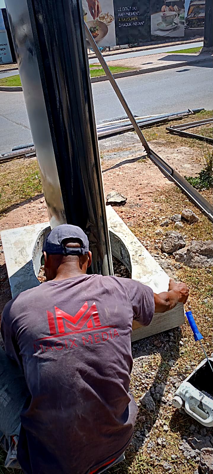 Technicien Magix Media scellant un support urbain